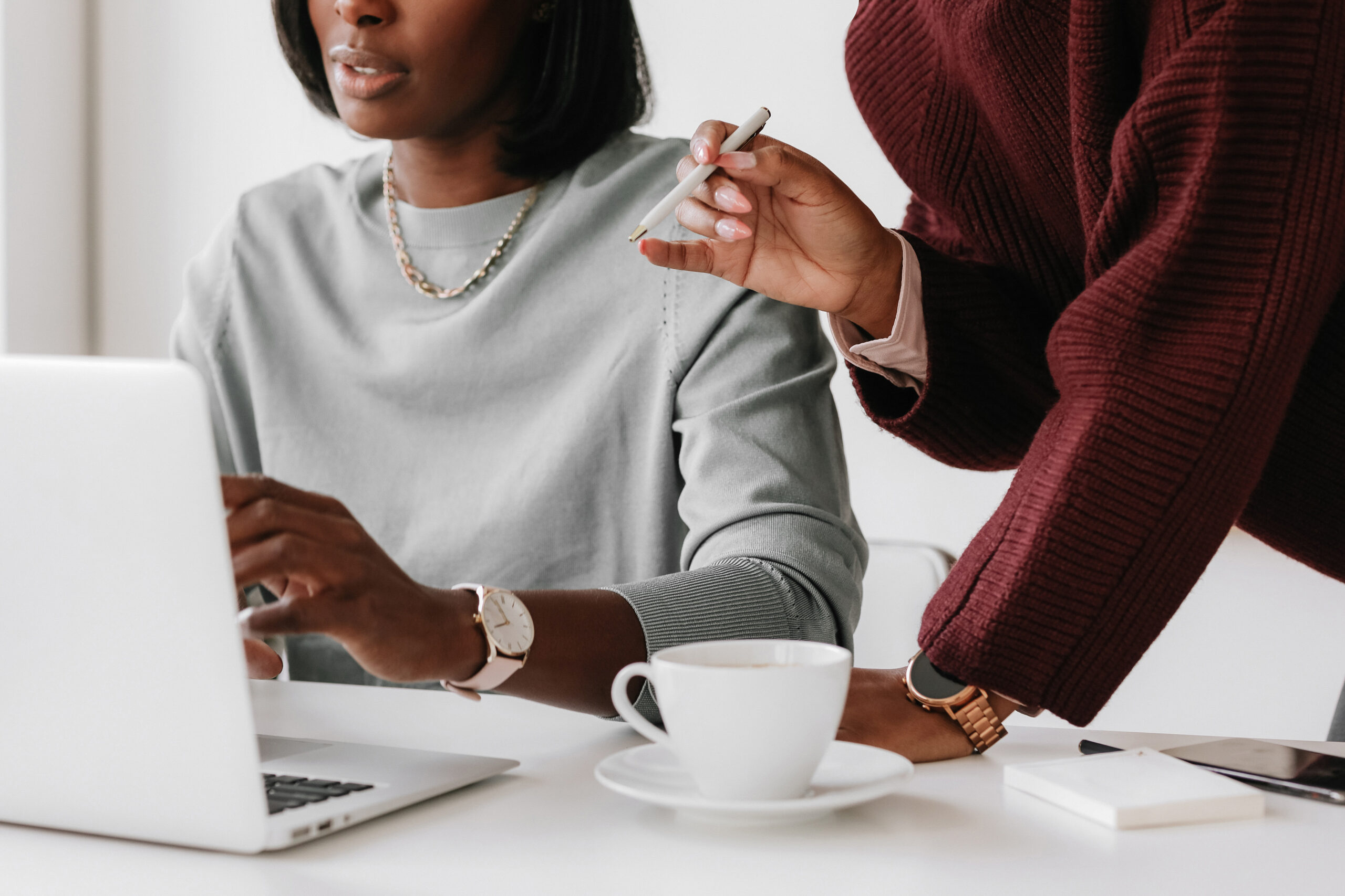 Woman of color business owner reviewing client contract and workflow documents at an organized, professional desk.