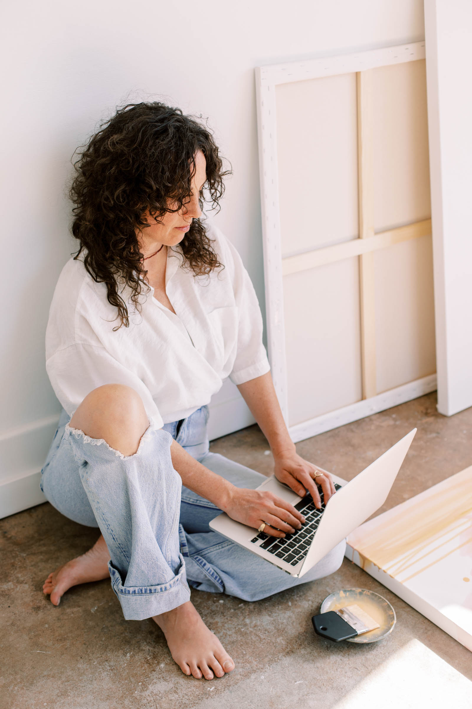 Woman of color business owner reviewing her website on a laptop, clean and minimal desk setup, warm natural light.
